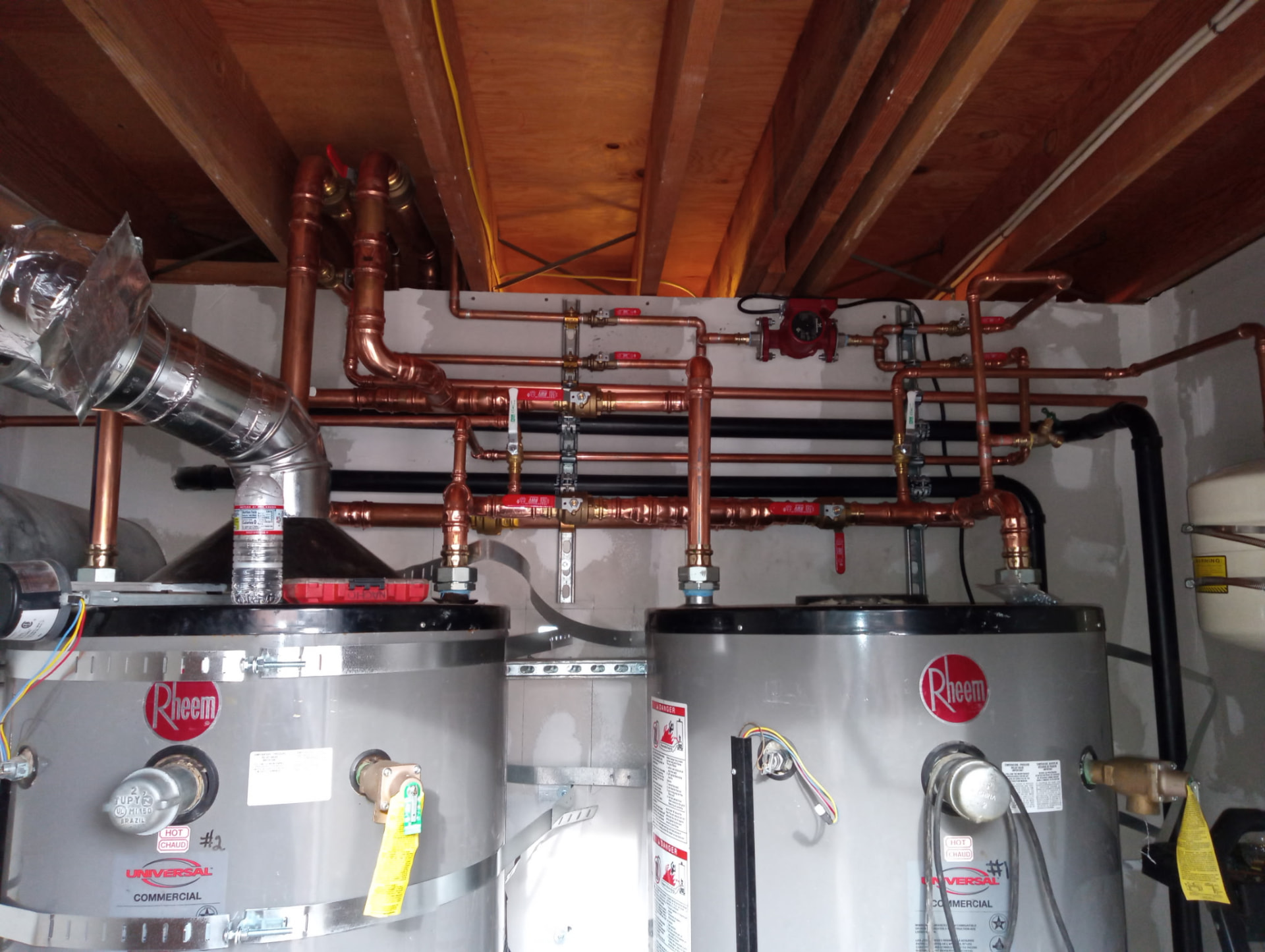 Copper recirculation piping above two commercial water heaters