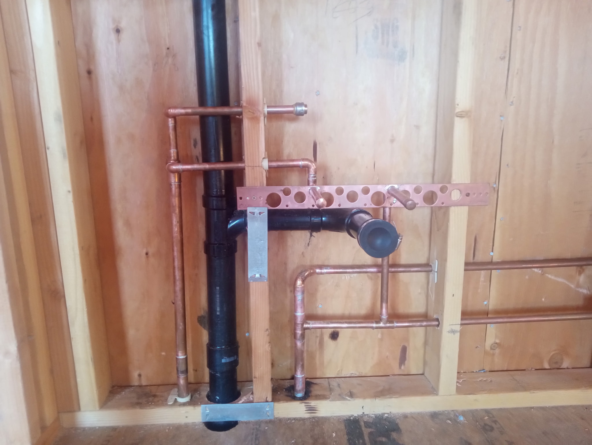 Bathroom plumbing rough-in with copper supply and black waste pipe