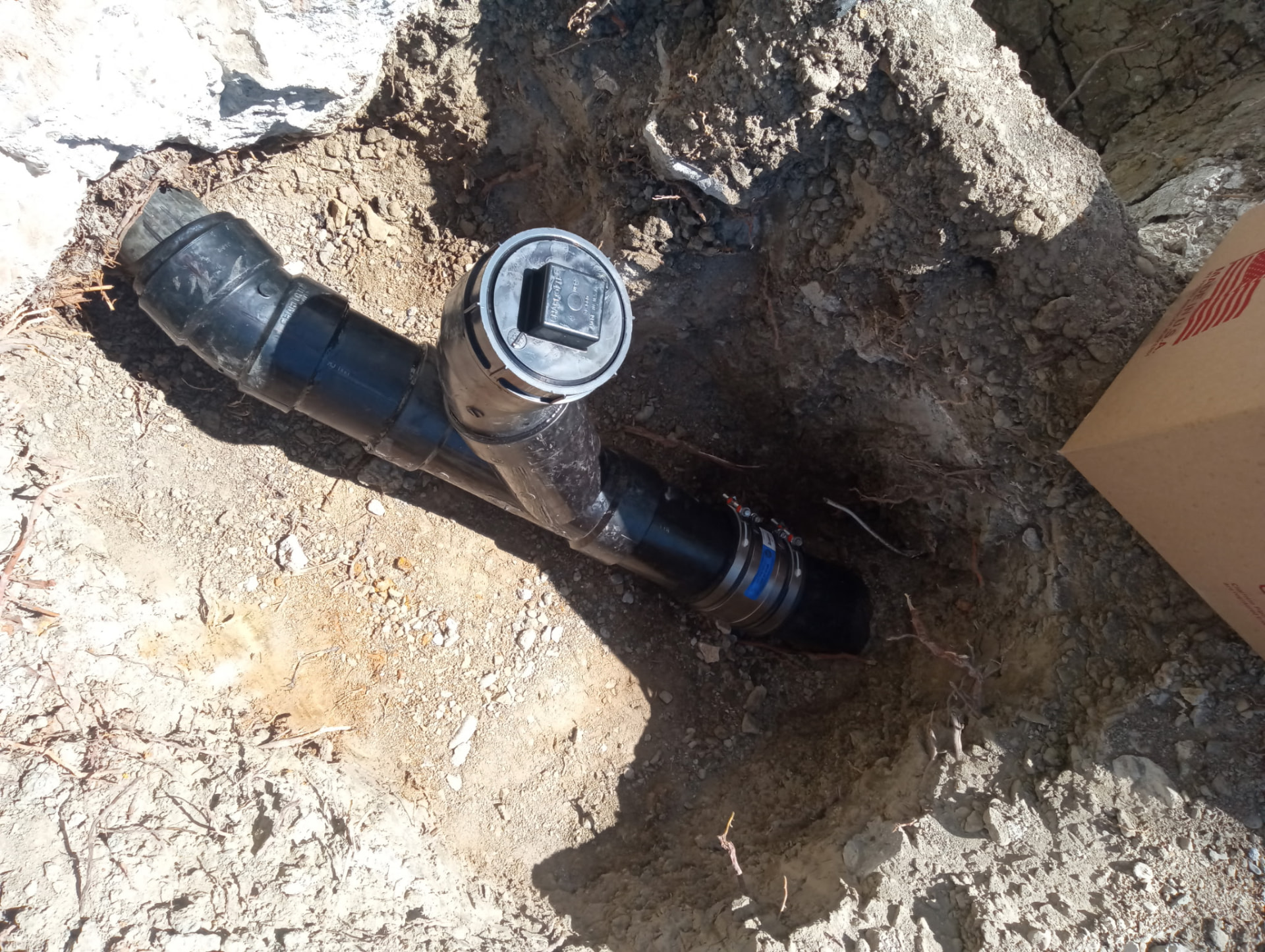 Newly installed sewer cleanout fitting in an excavated trench