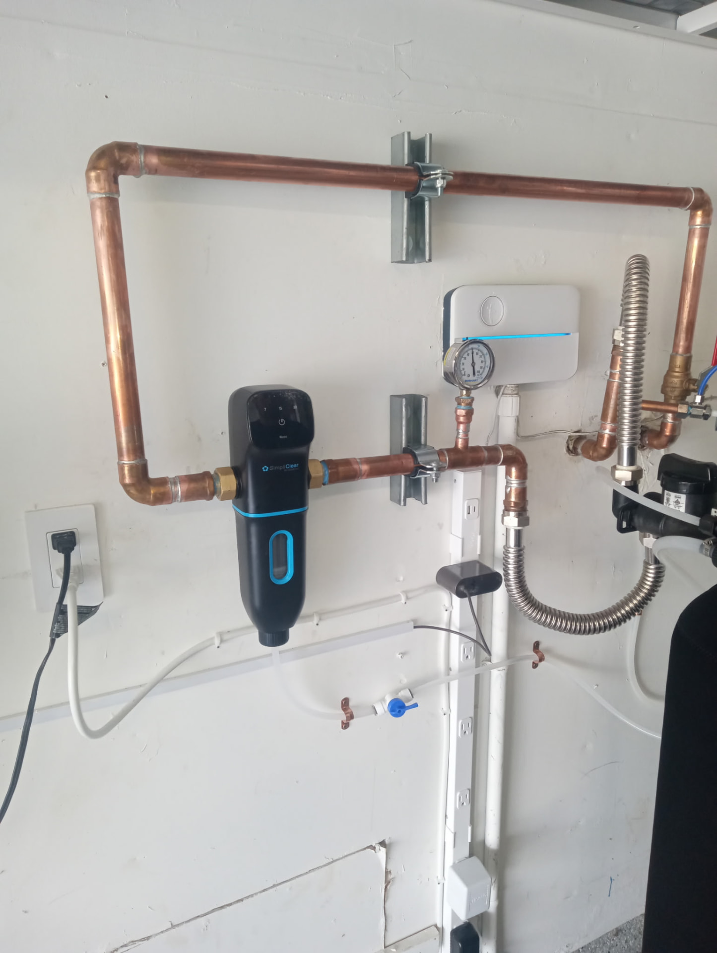 Whole home water filtration unit plumbed into copper lines in a garage