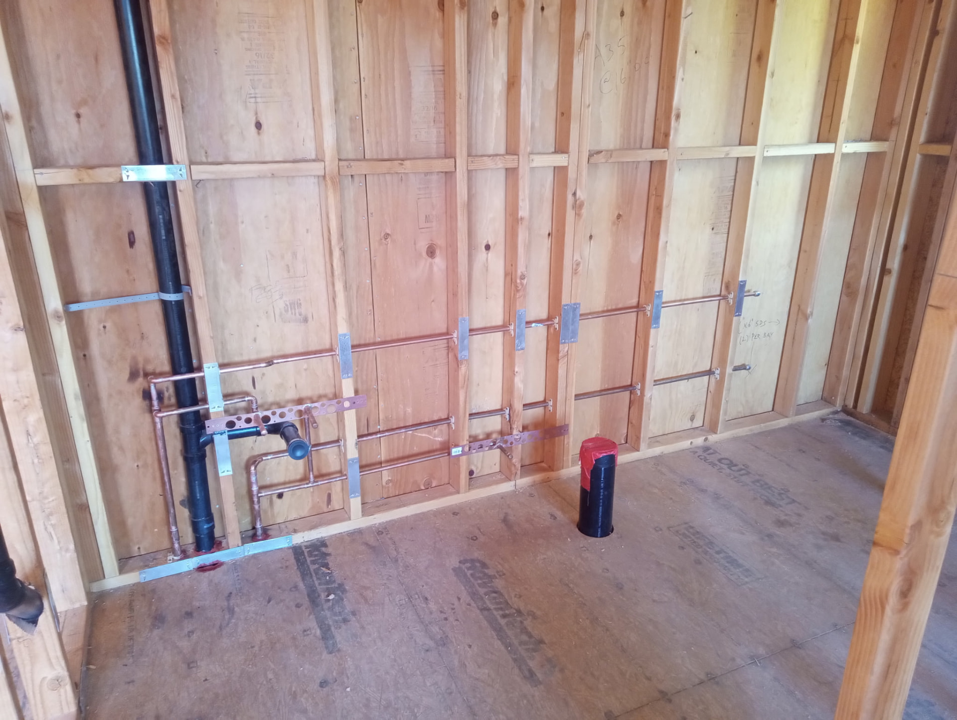 Framed wall with copper supply lines strapped and nail plates installed