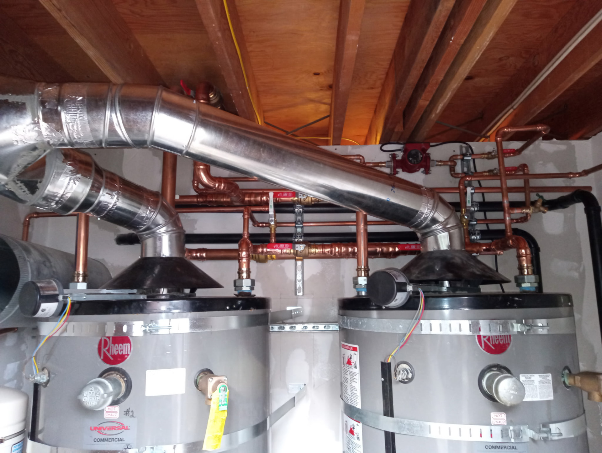 Copper manifold above two commercial Rheem water heaters