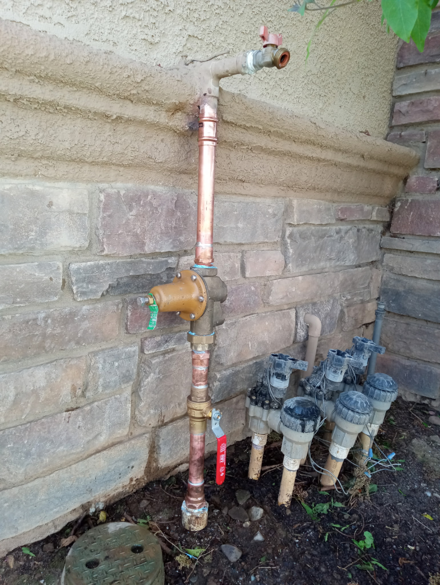 Copper water line with new pressure regulator mounted on a stone wall