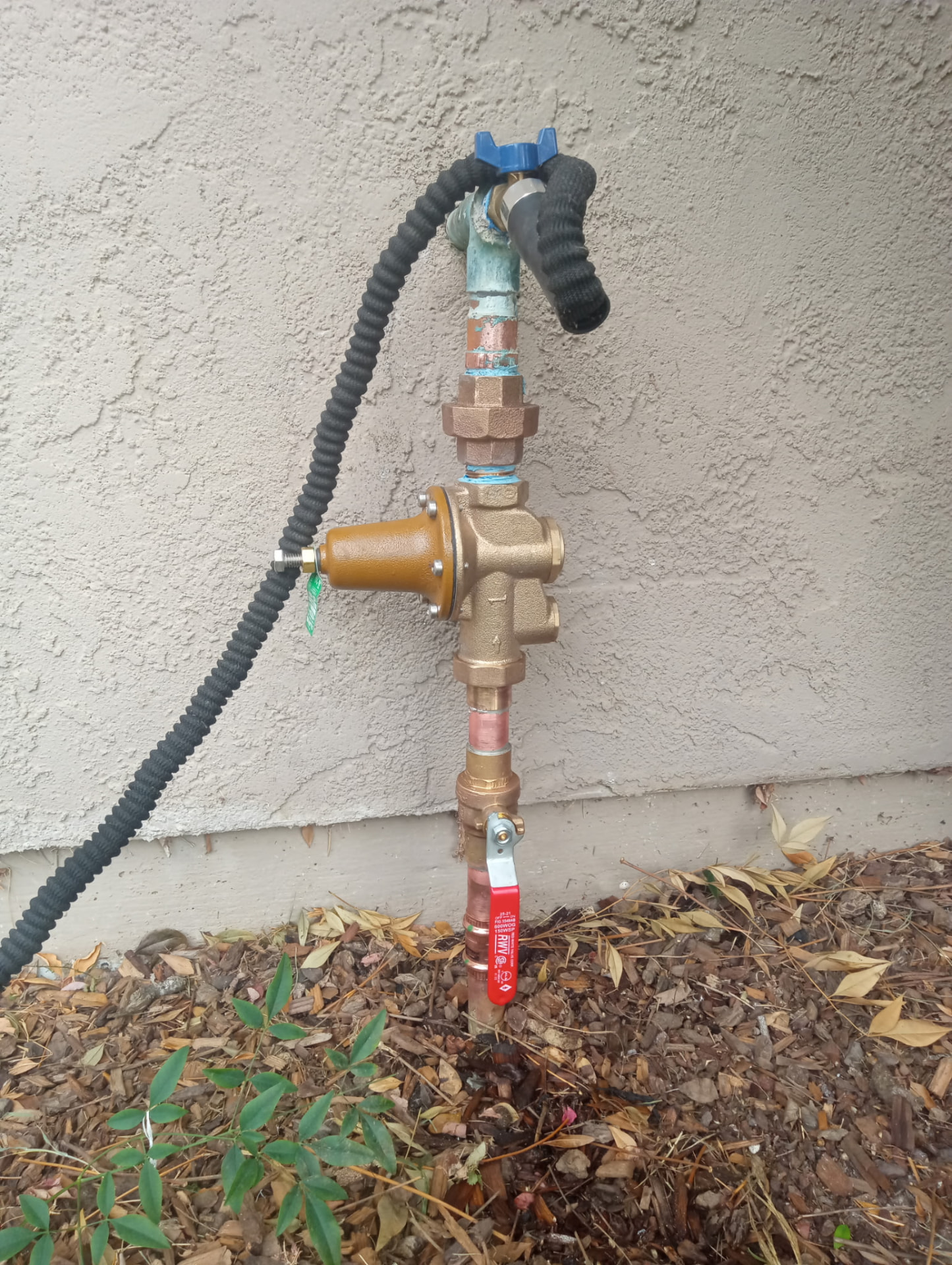Brass pressure regulator and shutoff valve on an exterior wall